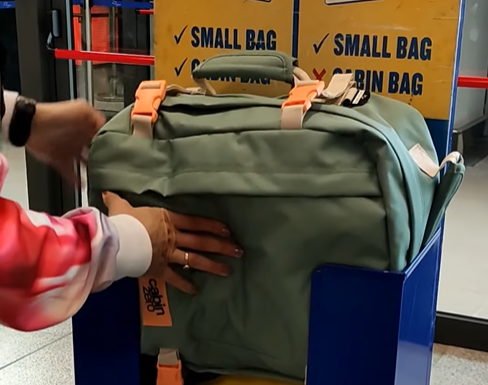 Cabin Max Metz Stowaway 20L Travel Bag being measured at airport luggage check, showing underseat compliance and 16x10x8 inch cabin size verification.