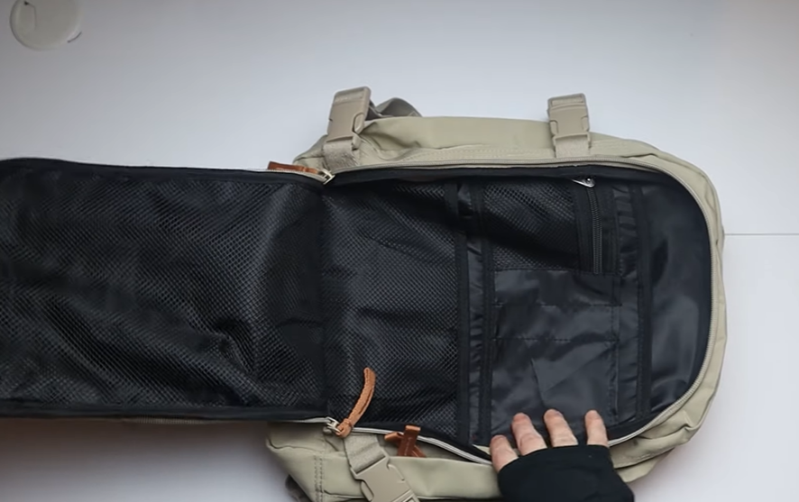 Traveler testing the Cabin Max Metz Stowaway 20L Travel Bag, showing real-life underseat fit, compact 16x10x8" size, and suitcase-style opening during packing.